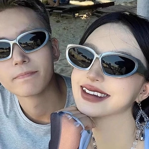 Close-up of Y2K steampunk sports sunglasses with silver metallic frames on beach
