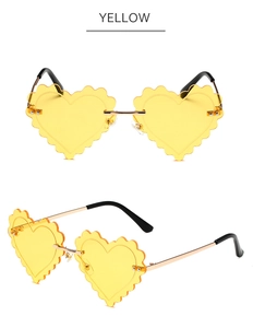 Detail of yellow heart-shaped rimless sunglasses with wavy cut edges and gold metal temples