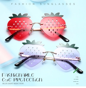 Detail of strawberry-shaped rimless sunglasses with green leaf accents and gold metal frame