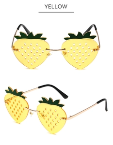Detail of yellow strawberry shaped sunglasses with green leaf accents and gold metal frame
