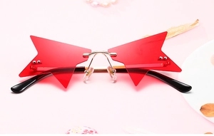 Détail de lunettes de soleil étoile sans monture avec verres rouges et pont doré