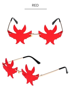 Detail of red bat-shaped rimless sunglasses with gold metal frame and lens engravings