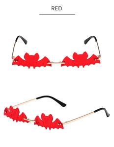 Detail of red bat-shaped frameless sunglasses with gold metal temples for parties