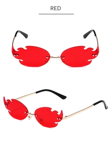 Detail of red flame-shaped rimless sunglasses with gold metal frame and fire jagged edges