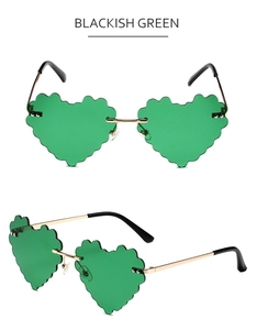 Detail van hartvormige zonnebril met golvende randen en goudkleurig metalen frame groen