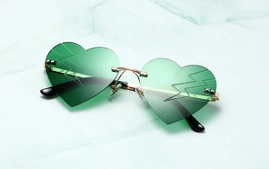 Close-up of heart-shaped green lenses with lightning bolt engraving and gold metal frames