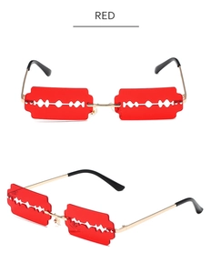 Detailed close-up of red razor blade shaped lenses on golden metal sunglasses frame