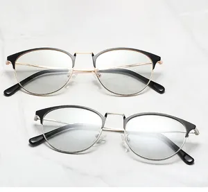 Détail de montures de lunettes demi-cerclées en métal noir, or et argent sur marbre