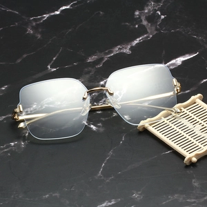 Fashionable rimless square blue light glasses with gold metal frame on marble surface