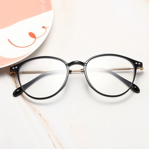 Detailed close-up of retro black and gold metal eyeglass frames on marble base