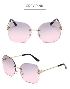 Detail view of rimless metal sunglasses featuring grey-pink gradient lenses and gold floral patterns