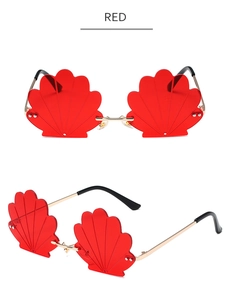 Detail view of red shell-shaped rimless sunglasses with gold metal frame and rivets