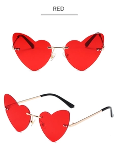 Close-up of heart-shaped rimless sunglasses with red tinted lenses and gold metal frames