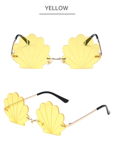 Detail of yellow flower-shaped rimless sunglasses with shell texture and gold metal frame