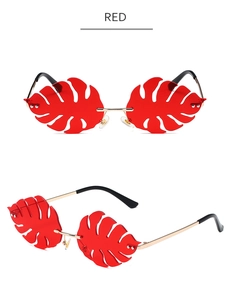 Macro shot of red leaf-shaped acrylic sunglasses lens with gold metal frame details