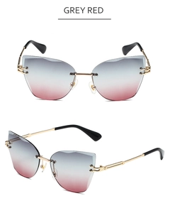 Detail view of rimless cat-eye sunglasses with grey to red gradient lenses and gold frames