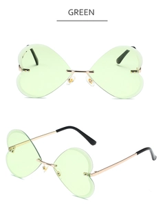 Détail de lunettes de soleil sans monture en forme de cœur vert avec cadre en métal doré