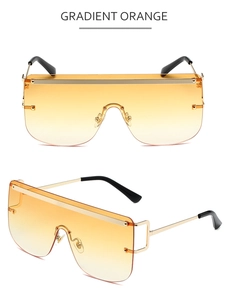 Macro detail of oversized shield sunglasses with gradient orange lens and gold frames