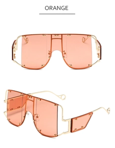 Detail of oversized orange shield sunglasses featuring gold studs and metal temples