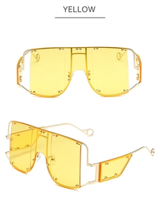 Detail of yellow one-piece shield sunglasses with gold rivets and metallic frame
