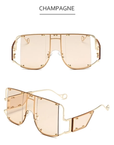 Detail view of champagne oversized shield sunglasses with gold metal frame and rivets