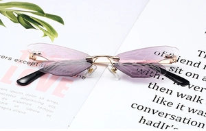 Detail of dragonfly wing sunglasses featuring purple gradient lenses and gold metal frame
