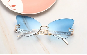 Detail of blue gradient butterfly sunglasses with gold hollow metal temples on marble