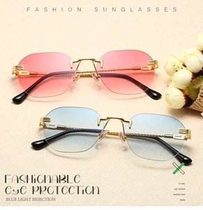Close-up of rimless gradient sunglasses with gold metal frames and twisted temple detail