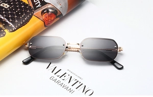 Detail einer randlosen eckigen Sonnenbrille mit gedrehten Goldbügeln und grauen Gläsern