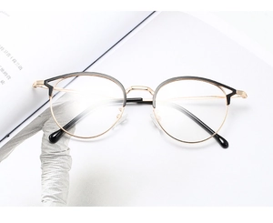 Détail de la monture de lunettes ronde en métal noir et or sur un magazine blanc