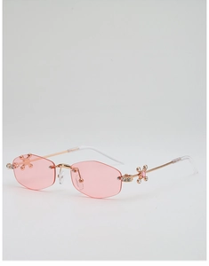 Détail de lunettes de soleil sans monture roses avec cadre doré et ornements en strass brillants