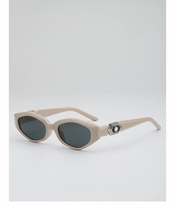 Close-up of beige polygonal sunglasses with silver hexagonal metal hinge and white gem