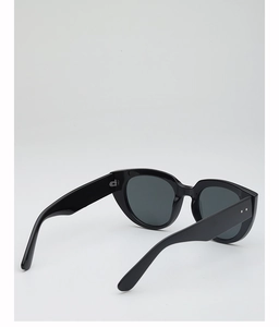 Close-up of black oversized sunglasses with silver rivet detail and dark lenses