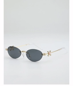 Detail of rimless oval sunglasses with gold temples, pink rhinestones and dark lenses