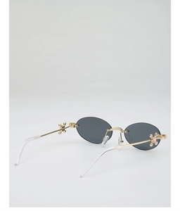 Detail of gold metal hinge with cross floral pattern and pink crystal on oval sunglasses