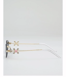 Detail of gold metal temple with pink gemstone and cross decoration on rimless sunglasses
