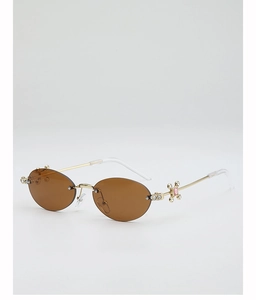 Detail of oval rimless sunglasses with gold temples and pink gemstone accents
