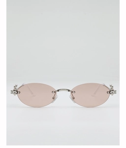 Detail of pink oval rimless sunglasses featuring silver metal hinges and rhinestone accents
