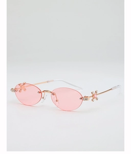 Detail of pink oval rimless sunglasses with gold metal frame and rhinestone cross accents