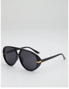 Close-up of black aviator sunglasses with gold metal accents on the frame temples