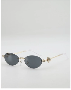 Close-up of luxury oval sunglasses with gold metal temples and sparkling rhinestone clusters
