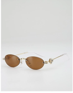 Close-up of luxury oval rimless sunglasses with gold metal temples and crystal accents