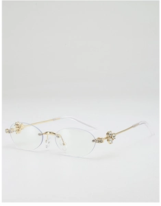 Close-up of golden rimless oval sunglasses with crystal flower detail on metal temples