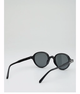 Detail view of round frame sunglasses showing silver hinge accents and thick black temples