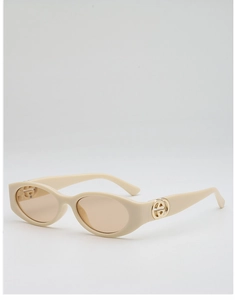 Detailed close-up of cream oval sunglasses with golden metal logo and tinted lenses