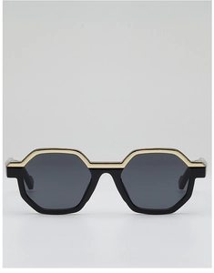 Detail of trendy polygonal sunglasses with gold metal top trim and sleek black frame