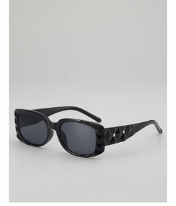 Close-up of black square sunglasses featuring geometric faceted edges and silver rivets