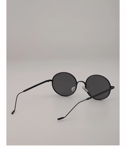 Détail de lunettes de soleil ovales en métal noir avec branches fines et verres gris foncé