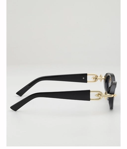 Detail of black sunglasses with bold golden spiked geometric metal hardware on temple