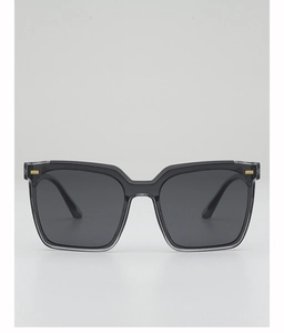 Detailed close-up of square black sunglasses with gold metal studs and grey lenses